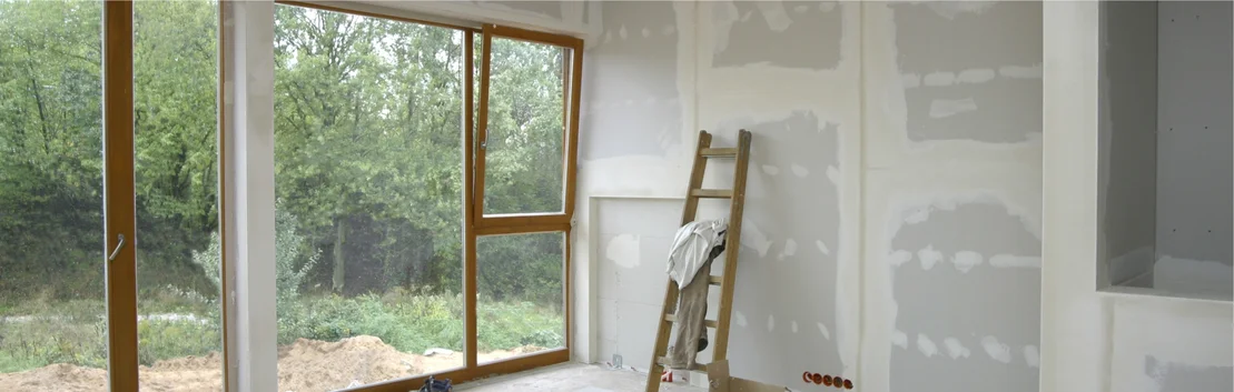 Innenraum mit Trockenbauw&auml;nden, Holzfenster und Leiter, geeignet f&uuml;r DIY-Renovierungsprojekte.