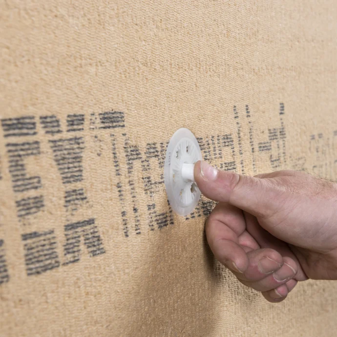 Person montiert Dämmstoffplatte mit Tellerdübel an der Wand für sichere Befestigung beim Renovieren.