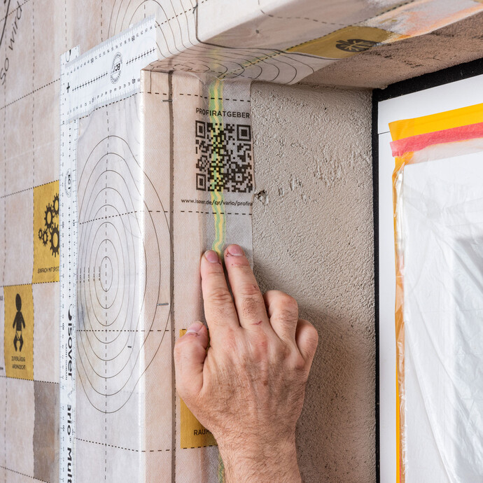 Die Dampfbremse wird auf die Klebe-Dichtmasse lückenlos und fest angedrückt. So klebt die Folie fest in der Laibung. Anleitung zum Einbau einer Dampfbremse.