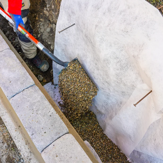 Mise en place de gravier dans la couche de drainage pour l'isolation du mur.