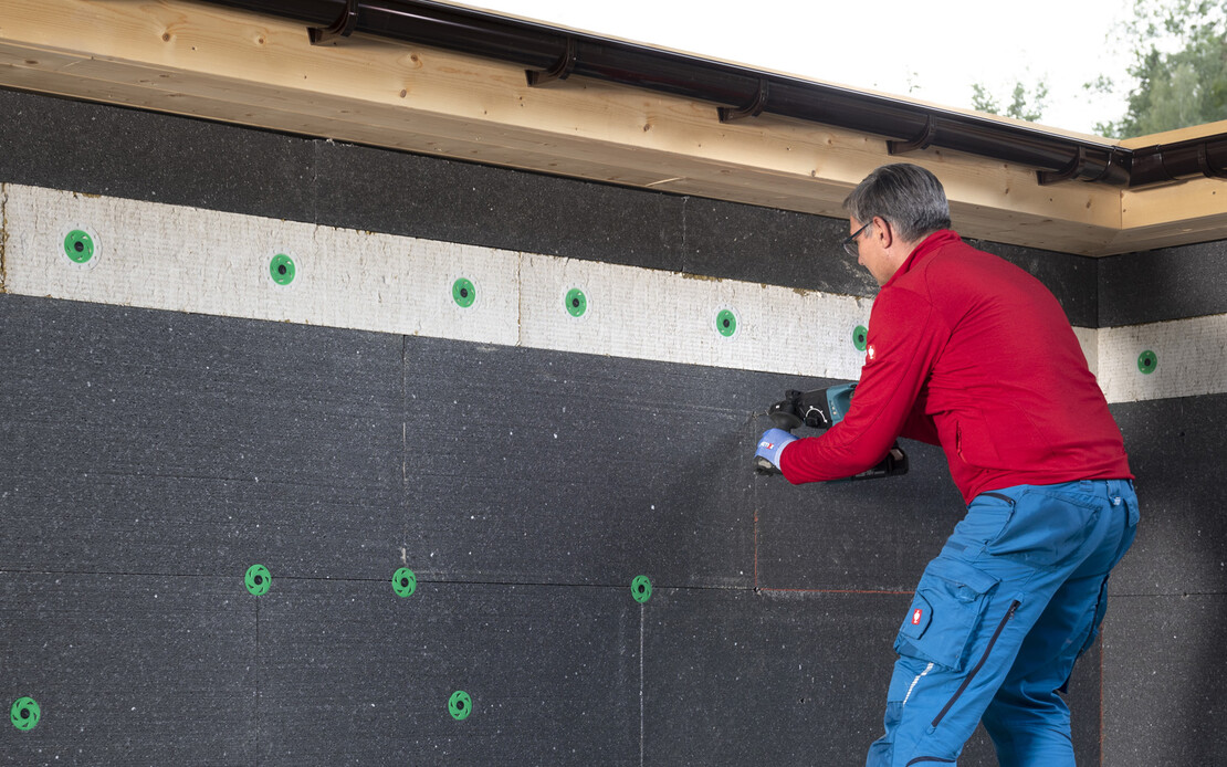 Heimwerker bohrt Löcher, um die EPS-Dämmplatten an der Fassade mit dem Thermotop Schlagdübel H2 plus zu befestigen.