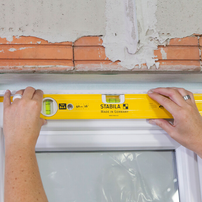Coller la baguette de finition dans le linteau de la fenêtre, alignée avec un niveau à bulle.
