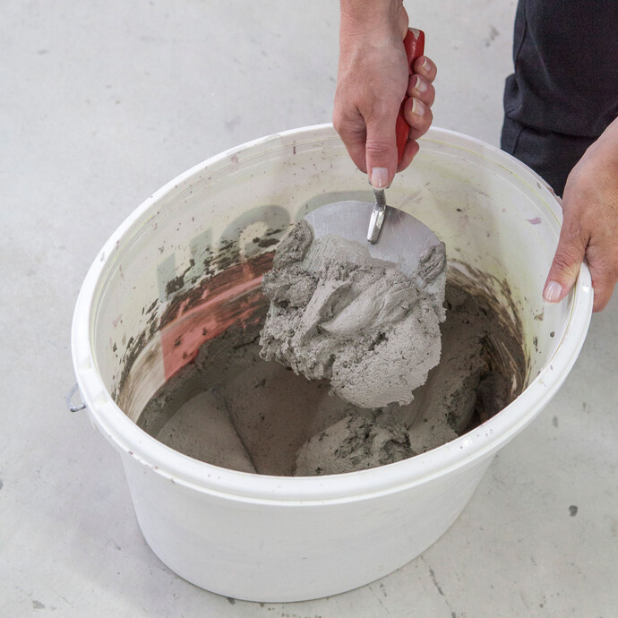 Détail - seau et mortier d'enduit mélangé : le mortier de maçonnerie et d'enduit est mélangé à la main.