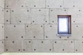 Wand mit fachgerecht angebrachten Dämmplatten und offenem Fenster, optimal isoliert für energieeffiziente Renovierung.