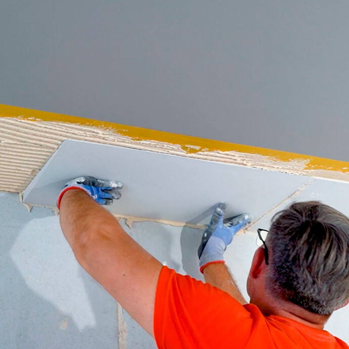 Heimwerker klebt den nächsten Anschlusskeil an die Decke.