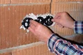 Mann installiert Unterputzdosen in Mauerwerk, Vorbereitung für Elektroinstallation im Heimwerkerprojekt.