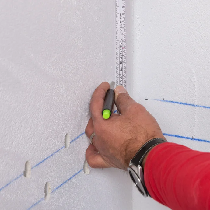 Handwerker zeichnet die dritte Bohrlochreihe 5 cm über der zweiten an. Die dritte Bohrlochreihe beträgt eine Länge von 15 bis 20 cm. Es wird alle 5 cm eine Markierung gesetzt.