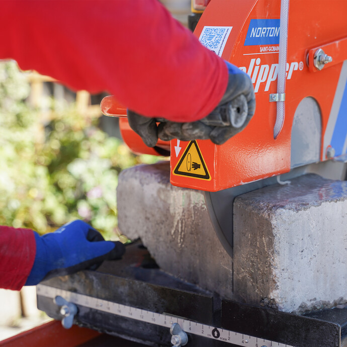 Heimwerker sägt Mauersteine im Garten mit der Norton Clipper Steinsäge, um eine Gartenmauer zu bauen.