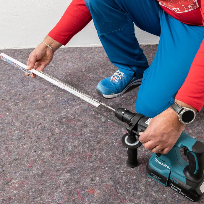 Handwerker misst die optimale Länge des Bohrers der Bohrmaschine ab.