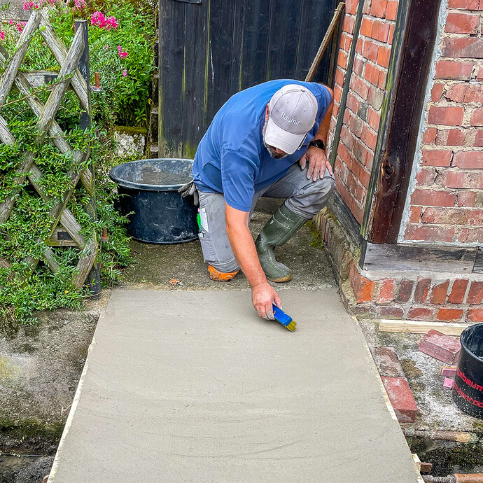 Aufrauen der frischen Betonoberfläche mit Bürste für bessere Haftung.