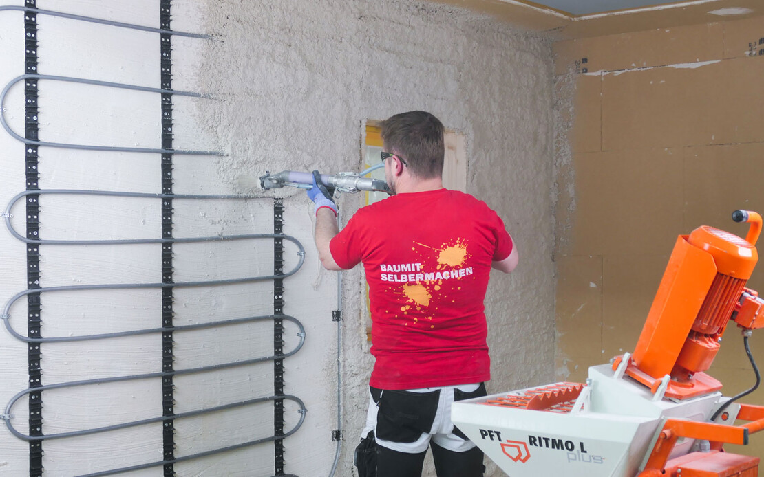 Handwerker verputzt die Wand mit einer Wandheizung professionell mit der Maschine PFT RITMO L.