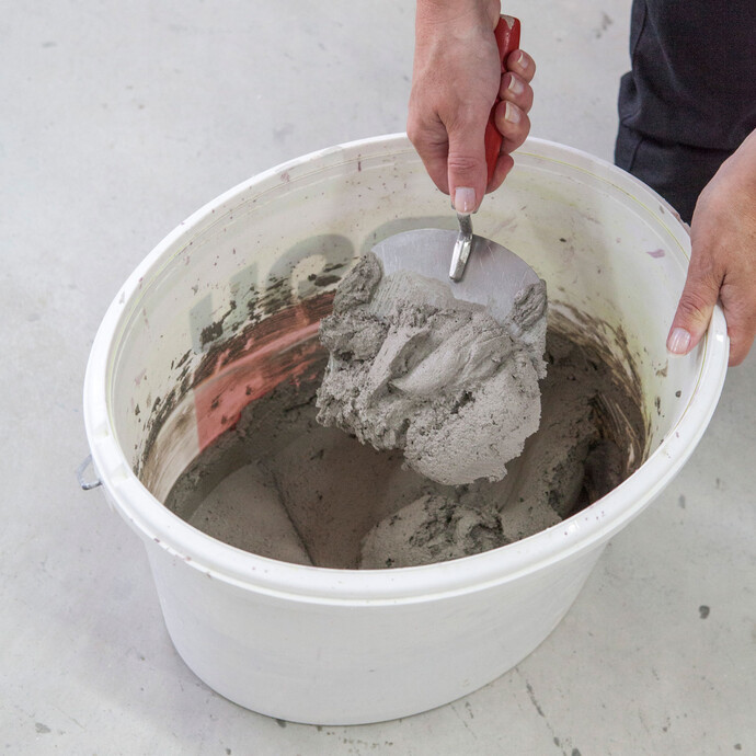 Le mortier est mélangé à la main dans un seau.