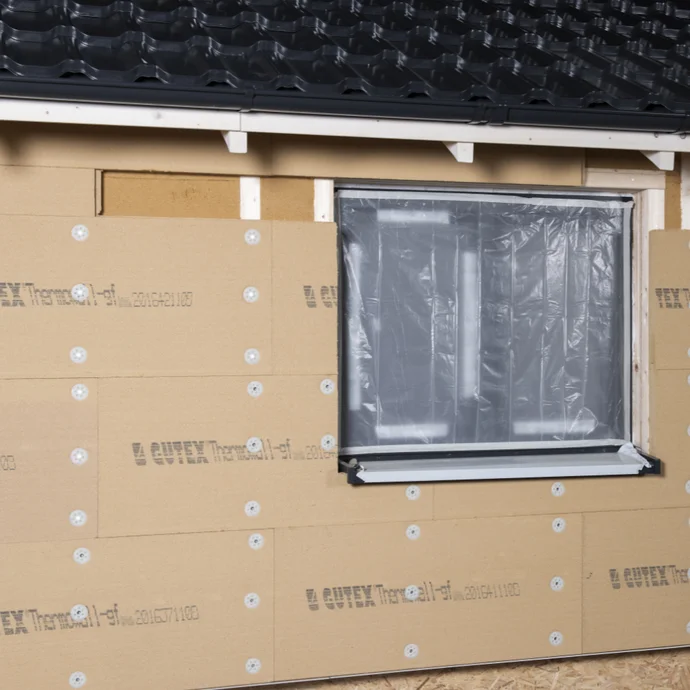 Fensterrahmen in isolierter Fassade, Setzen von Dämmmaterial für verbesserte Energieeffizienz im Heimwerkerprojekt.