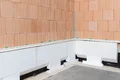 Les panneaux isolants pour soubassements de Baumit sont d'abord collés le long de la maison.