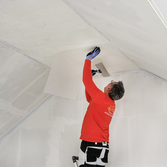 Le non-tissé de masticage est enfoncé dans la masse humide à l'aide d'une spatule de surface.