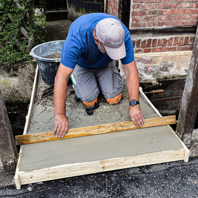 Abziehen des Gefällespachtels mit Abziehlatte entlang der Holzschalung.