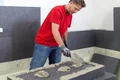 Heimwerker trägt mit einer Kelle Bautenkleber auf Dämmplatten auf für ein effizientes Wärmedämm-Verbundsystem.