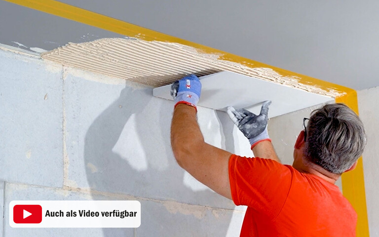 Anleitung Teaser - Laibunsplatte und Anschlusskeil im Antischimmel-System kleben. Person klebt den Kalziumsilikatplatte Anschlusskeil an die Decke. Die Anleitung ist auch als Video verfügbar.