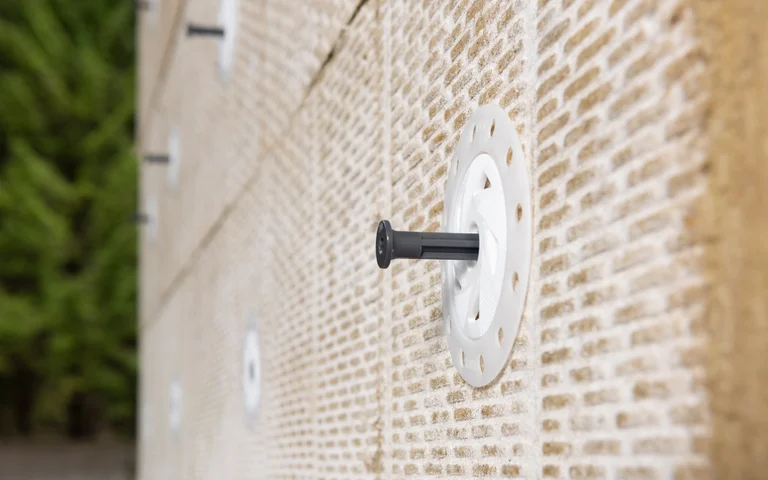 Panneaux isolants fixés à une façade à l'aide de chevilles à disque, idéaux pour une isolation thermique efficace et les projets de rénovation.