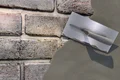 Truelle utilisée pour enduire un mur de briques avec un Enduit décoratif renforcé de fibres de Baumit. Idéal pour la rénovation intérieure et extérieure.