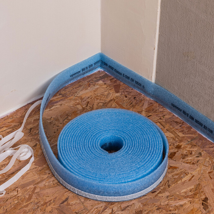 Innenecke eines Raums: Detailaufnahme des Randdämmstreifens auf Rolle. Der Randdämmstreifen ist in der Ecke befestigt.