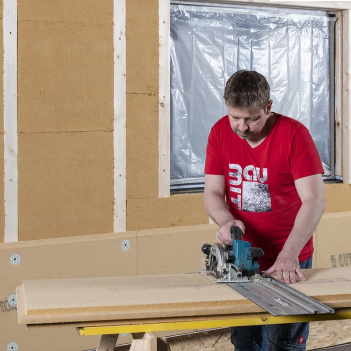 Heimwerker sägt Dämmplatte mit Handkreissäge für die Wandmontage, Schritt für Schritt Anleitung zur richtigen Durchführung.