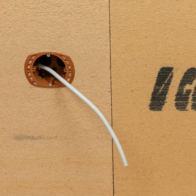 Fertig montierte Holzfaserdämmplatte mit eingebauter Geräte-Installationsdose und durchgeführtem Kabel.