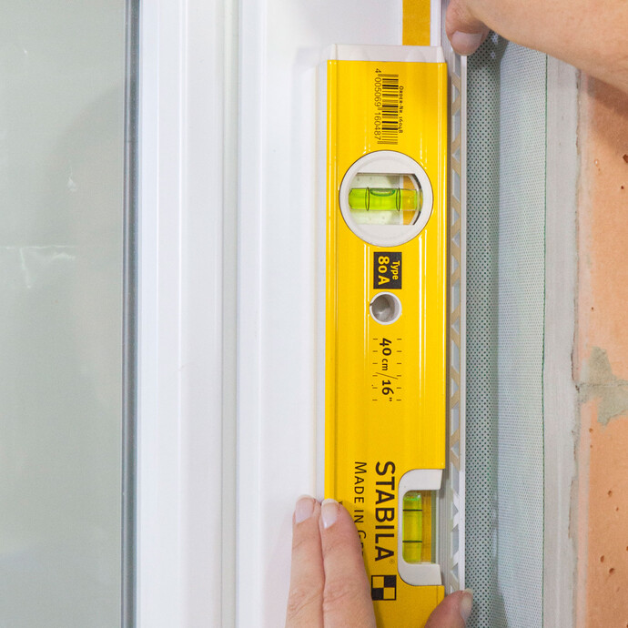 La position de la baguette de crépissage est vérifiée à l'aide d'un niveau à bulle.