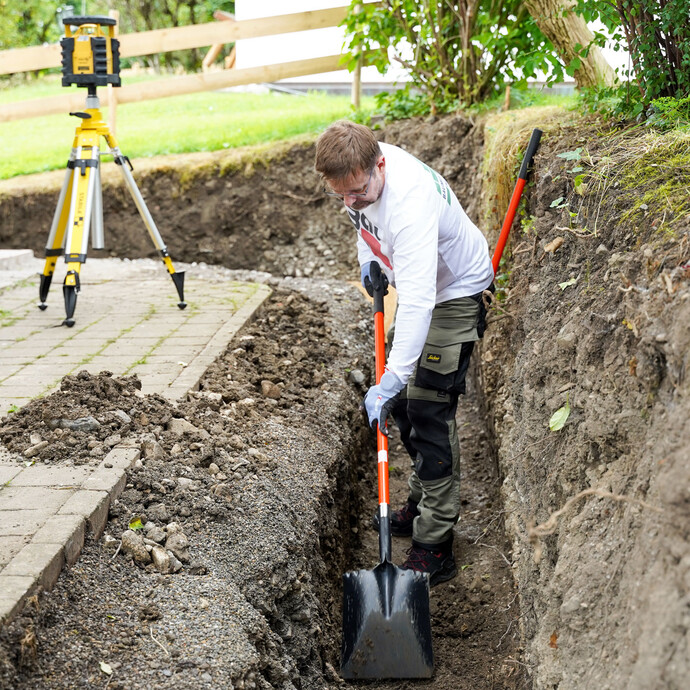 Arbeite die Baugrube nach und gleiche Unebenheiten mit den markierten Messpunkten aus.