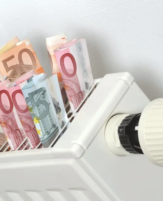 Des billets en euros posés sur un radiateur symbolisent les coûts énergétiques, dans le cadre des instructions de Baumit visant à réduire la consommation.
