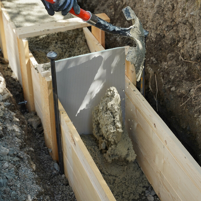 Beim Betonieren im Bereich der Dehnfuge wird der frische Trockenbeton vorsichtig mit der Schaufel von beiden Seiten eingefüllt, um ein Verrutschen der UniPlatte zu vermeiden.