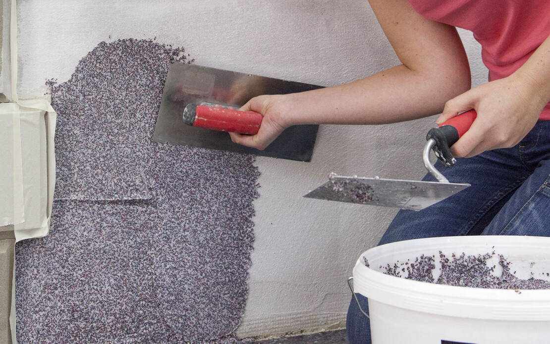 Der Baumit Mosaikputz,, Buntsteinputz, wird mit einer rostfreien Gl&auml;ttkelle aufgzogen.