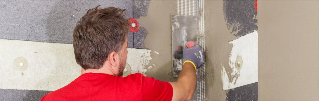 Un homme enduit les joints muraux &agrave; l&rsquo;aide d&rsquo;une taloche de lissage pour obtenir une finition parfaite lors de ses travaux de bricolage.