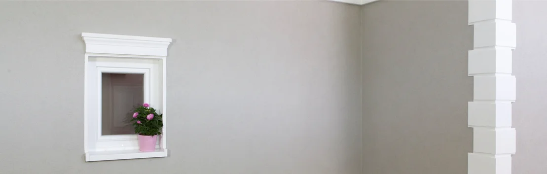 Mur peint en gris avec une petite fen&ecirc;tre et une plante d&eacute;corative, id&eacute;al pour les projets de bricolage avec les produits Baumit.