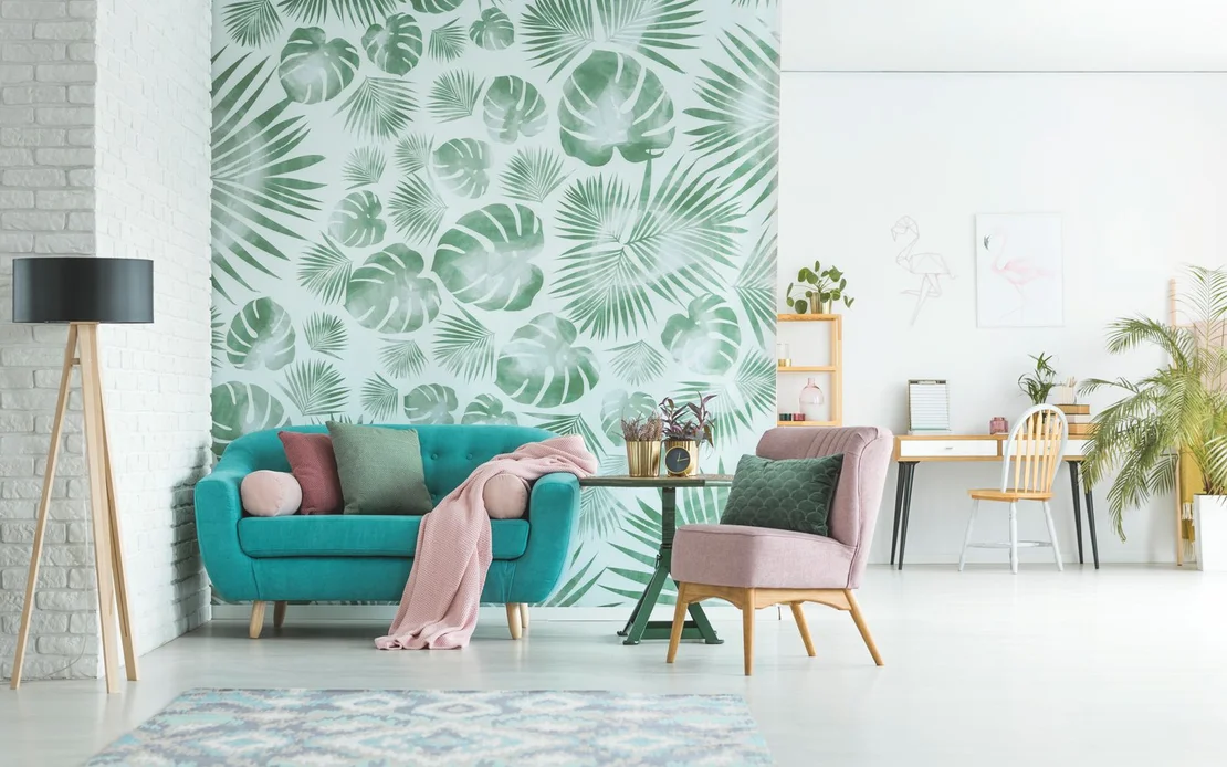 Salon moderne avec du papier peint &agrave; motifs tropicaux, un canap&eacute; turquoise, un fauteuil, un bureau et des plantes. Parfait &agrave; faire soi-m&ecirc;me.