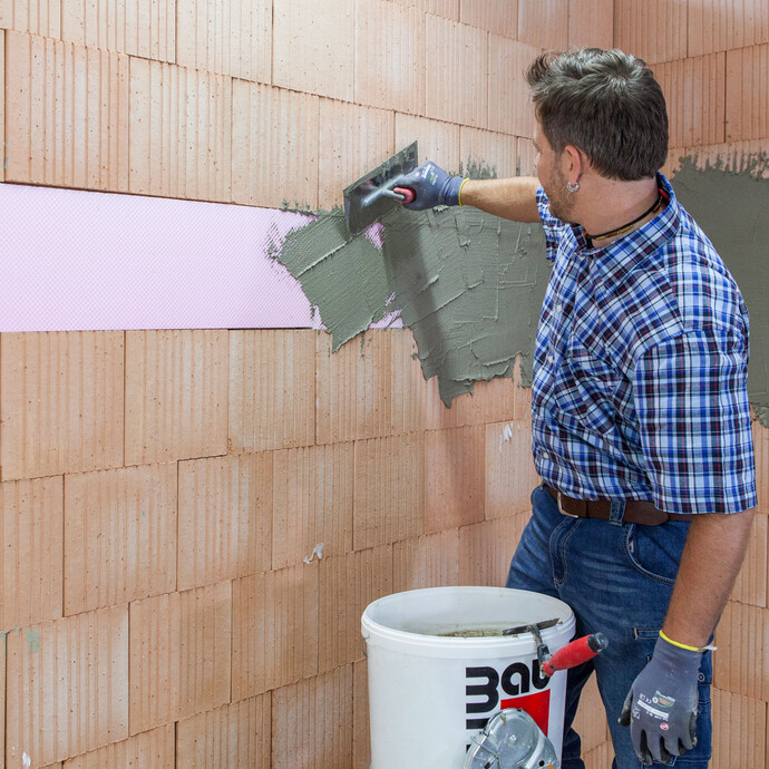 Heimwerker bringt den angemischten, frischen Putzmörtel bzw. Klebespachtel auf die XPS Platten auf.