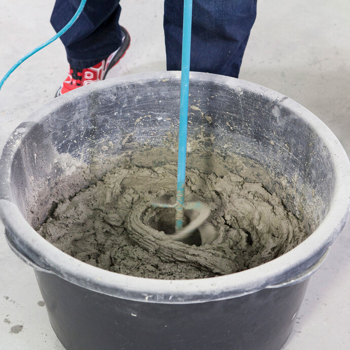 Detailfoto: Der Kalkzementputz wird mit einem elektrischen Rührgerät im Mörtelkübel angemischt.