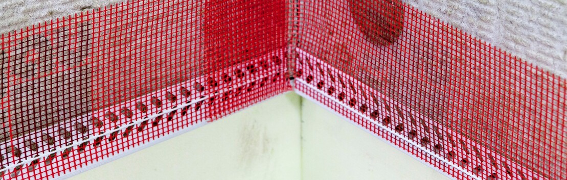 Gewebefahne des Sockelkantenprofils im Inneneckbereich &uuml;berlappend einsetzen