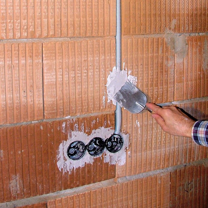 Das Leerrohr für die späteren Kabel, das zur Steckdose führt, wird mit dem frischen Gips fixiert.