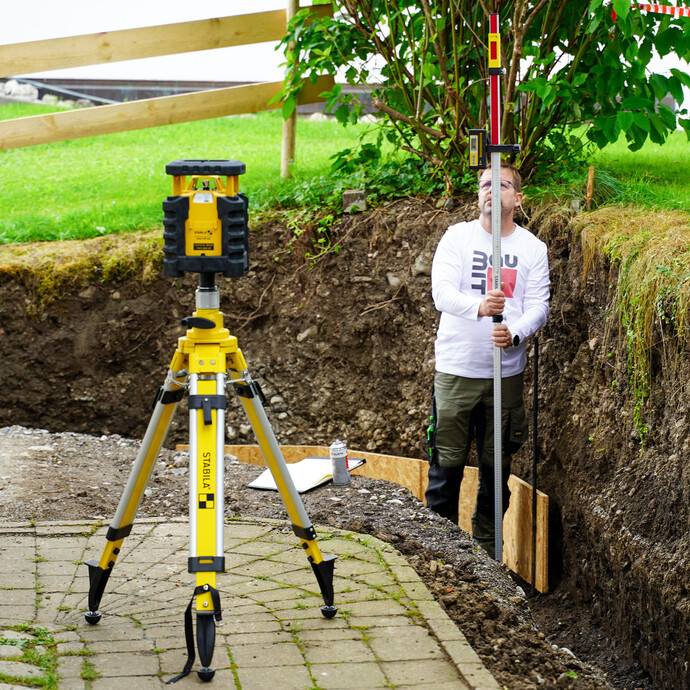 Prüfe die Baugrubensohle auf Unebenheiten und markiere die Messpunkte mit Markierspray.