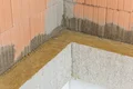 Isolation thermique à l'aide de panneaux isolants et d'enduit sur une maçonnerie en briques lors de la rénovation d'un intérieur.