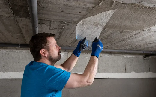 Heimwerker trägt Gewebe auf Betondecke zur Sanierung auf, mit Unterstützung von Baumit-Produkten für verbesserte Haltbarkeit.
