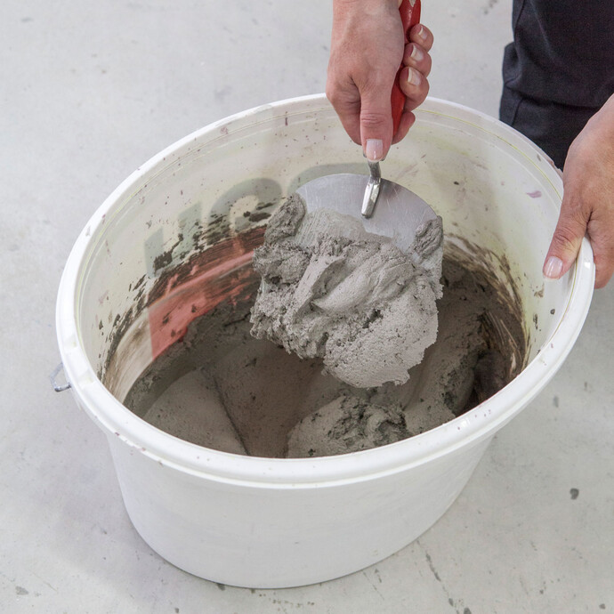 Le mortier pour rail d'angle Fix est mélangé dans un seau pour fixer les baguettes d'enduit rapide.