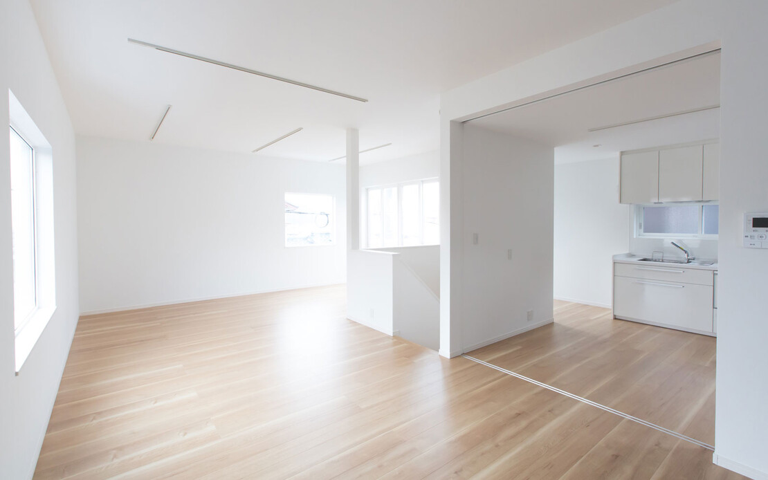 Heller, renovierter Raum mit Parkett, wei&szlig;en W&auml;nden und wei&szlig;er K&uuml;che.