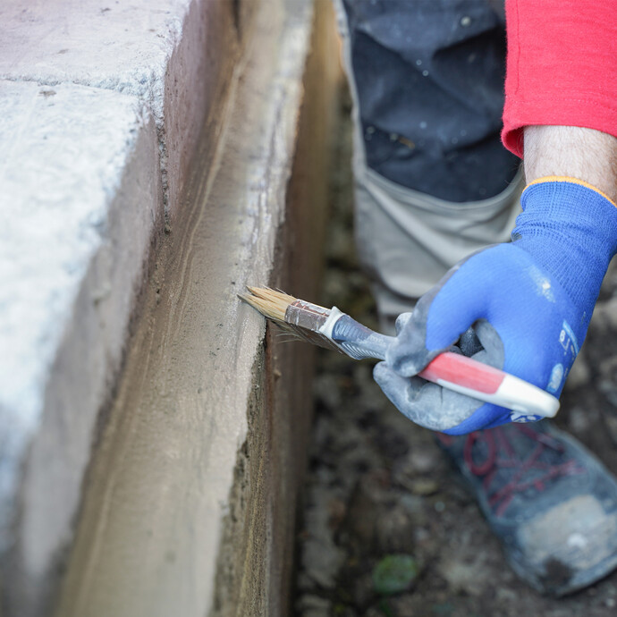Eine Person glättet Grate und Unebenheiten an der Hohlkehle mit einem Pinsel.