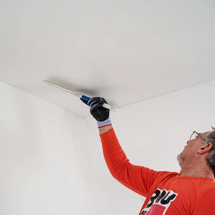 L'enduit au rouleau est lissé à l'aide d'une spatule de surface.