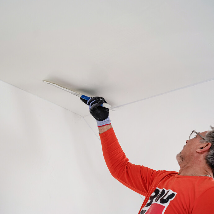 L'enduit au rouleau est lissé à l'aide d'une spatule de surface.