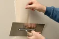Trockenbauwand spachteln: Anwendung von Fugenband und Glättkelle für nahtlose Übergänge im Innenausbau.