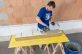 Un bricoleur pose des panneaux isolants sur une table en bois afin d’isoler un mur.