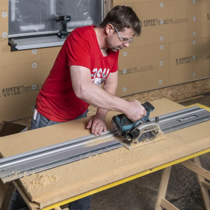 Heimwerker schneidet Holzplatte mit Handkreissäge auf Werkbank für Innenausbauprojekt.